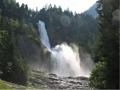 a waterfall in the middle of a river with trees at SAMOENS appartement proche du centre in Samoëns