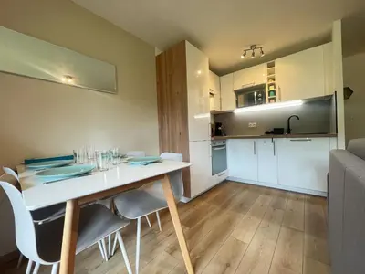 a dining room and kitchen with a white table and chairs at Studio rénové proche centre Samoëns avec balcon et proximité ski-bus - FR-1-624-159 in Samoëns