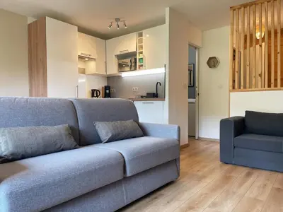 a living room with a blue couch and a kitchen at Studio rénové proche centre Samoëns avec balcon et proximité ski-bus - FR-1-624-159 in Samoëns