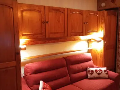 a living room with a red couch and wooden cabinets at Studio cabine pour 4 pers, animaux acceptés, internet, vue montagne - FR-1-629-136 in Samoëns