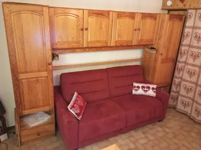 a red couch in a room with wooden cabinets at Studio cabine pour 4 pers, animaux acceptés, internet, vue montagne - FR-1-629-136 in Samoëns