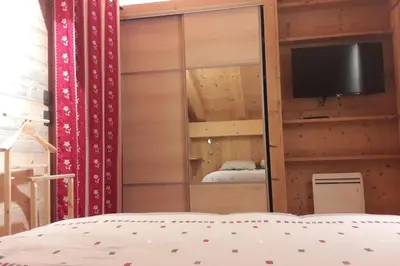 a bedroom with a mirrored closet with a tv and a bed at Appartement sur les pistes de Megève in Megève