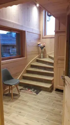 a staircase in a room with a chair and a vase of flowers at Appartement sur les pistes de Megève in Megève