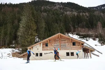 three people on skis in the snow in front of a cabin at La Ferme du Praz in Les Contamines-Montjoie