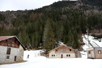 a person on skis in the snow next to buildings at La Ferme du Praz in Les Contamines-Montjoie
