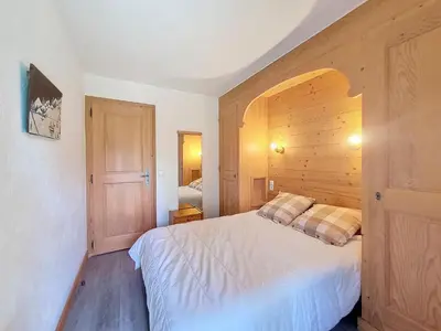 a bedroom with a white bed and a wooden wall at Appartement 2 chambres avec jardin au pied du Mont Blanc - FR-1-560-144 in Combloux