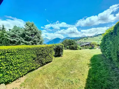 a hedge in front of a field with mountains in the background at Appartement 2 chambres avec jardin au pied du Mont Blanc - FR-1-560-144 in Combloux