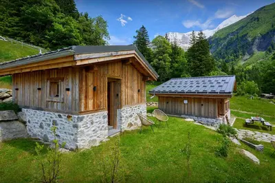 a couple of buildings in a field with mountains at Petit Mazot La Chandelle - OVO Network in Bionnassay