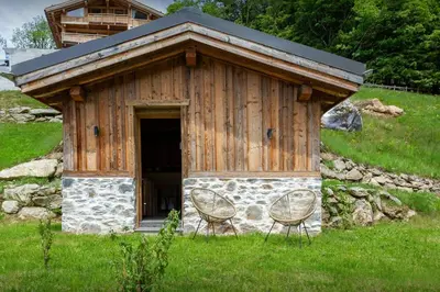 a small cabin with two chairs in the grass at Petit Mazot La Chandelle - OVO Network in Bionnassay