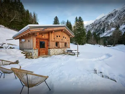 a log cabin in the snow with a table and benches at Grand Mazot La Chandelle - OVO Network in Bionnassay