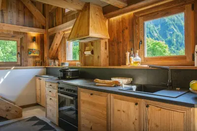 a kitchen with wooden cabinets and a sink and a stove at Grand Mazot La Chandelle - OVO Network in Bionnassay