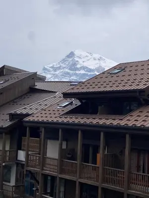 a snow covered mountain in the distance behind two buildings at Le Cocon des Carroz, au centre de la station et proximité des pistes, apt 4 pers in Arâches-la-Frasse