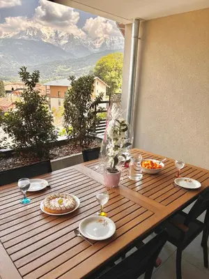 a wooden table with plates of food and wine glasses at Vue Mont-Blanc aux pieds des pistes - location cozy pour 2 personnes in Domancy