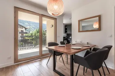 a dining room with a table and chairs and a balcony at Le 203 - Proche telecabine - centre ville in Saint-Gervais-les-Bains
