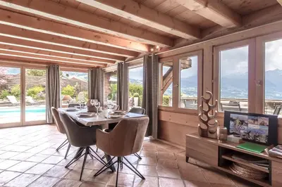 a person laying on a couch on a patio with a sunset at Chalet Hygge - Piscine - Calme in Saint-Gervais-les-Bains