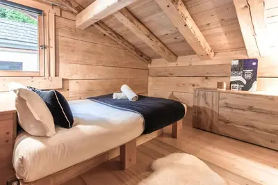 a bedroom with a large bed in a wooden wall at Chalet Hygge - Piscine - Calme in Saint-Gervais-les-Bains