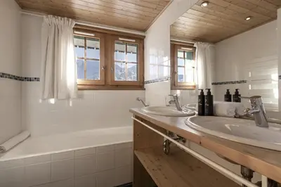 a bathroom with a tub and two sinks and a bath tubermottermott at Chalet Marie Paradis vue Mont Blanc in Saint-Gervais-les-Bains