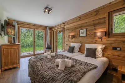 a bedroom with a large bed with wooden walls and windows at Chalet 1000 in Les Houches