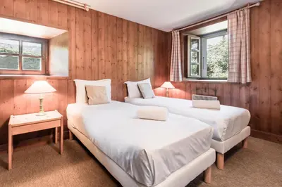 two beds in a room with wooden walls and windows at La Poya Bas in Les Houches