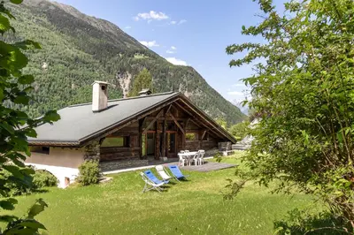 a log cabin with chairs and a table in the grass at La Poya Bas in Les Houches