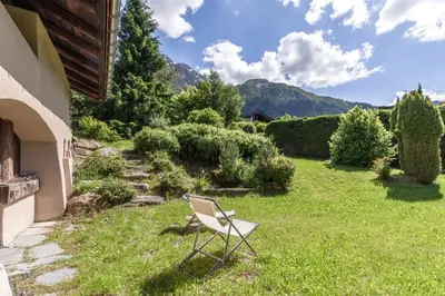a chair sitting in the grass next to a house at La Poya Bas in Les Houches