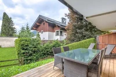 a patio with a glass table and chairs on a deck at Appartement Rothschild - garage - Welkeys in Megève