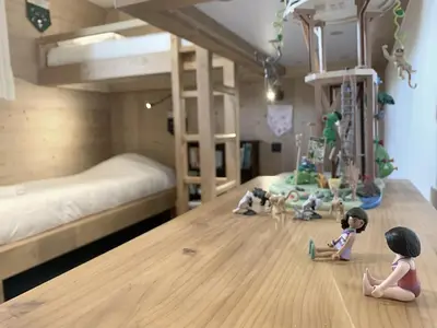 two dolls sitting on the floor of a bedroom with bunk beds at Chalet Le Splendide in Saint-Gervais-les-Bains