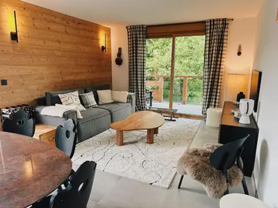 a living room with a couch and a table at L'Olympe de Combloux - Terrasse & balcon sur la forêt in Combloux