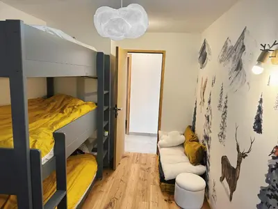 a bedroom with a bunk bed with yellow sheets at L'Olympe de Combloux - Terrasse & balcon sur la forêt in Combloux