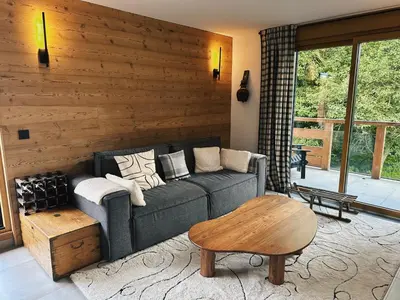 a living room with a couch and a wooden wall at L'Olympe de Combloux - Terrasse & balcon sur la forêt in Combloux