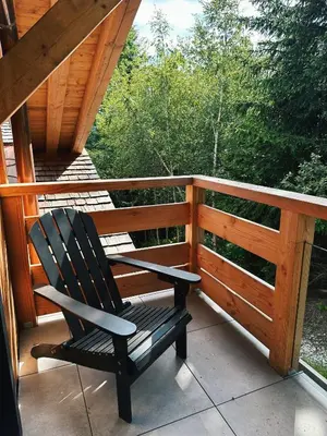 a rocking chair sitting on the porch of a cabin at L'Olympe de Combloux - Terrasse & balcon sur la forêt in Combloux