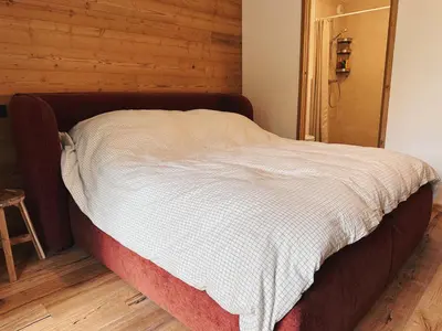 a bed in a room with a wooden wall at L'Olympe de Combloux - Terrasse & balcon sur la forêt in Combloux