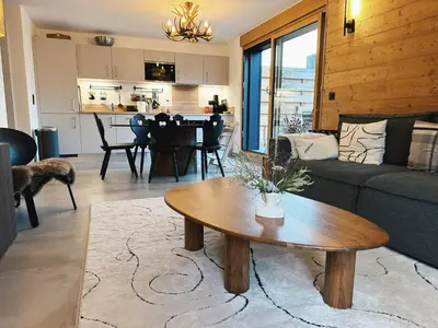 a living room with a couch and a table at L'Olympe de Combloux - Terrasse & balcon sur la forêt in Combloux