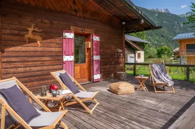 a deck with rocking chairs and a log cabin at Cocooning small chaming chalet with garden in Chamonix-Mont-Blanc