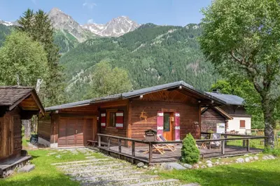 a log cabin with mountains in the background at Cocooning small chaming chalet with garden in Chamonix-Mont-Blanc