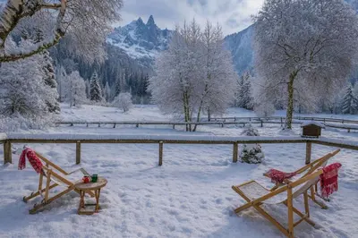 two wooden benches covered in snow with mountains in the background at Cocooning small chaming chalet with garden in Chamonix-Mont-Blanc