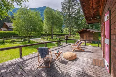 a deck with chairs and a table and a log cabin at Cocooning small chaming chalet with garden in Chamonix-Mont-Blanc