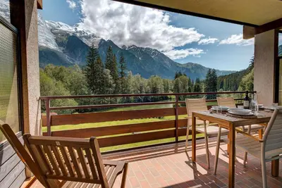 a table and chairs on a balcony with a view of mountains at Apartment Cristal des Glaces, Mont Blanc View, Alpes Travel, sleeps 6 in Chamonix-Mont-Blanc
