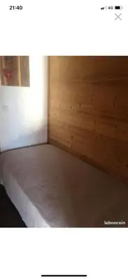 a room with a bed with a wooden wall at standing 4 étoiles in Demi-Quartier