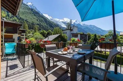 a table and chairs on a balcony with mountains at Heart of Chamonix Lovely and cosy 2 bedrooms, terrace, parking in Chamonix-Mont-Blanc