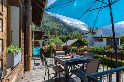 a table and chairs on a balcony with an umbrella at Heart of Chamonix Lovely and cosy 2 bedrooms, terrace, parking in Chamonix-Mont-Blanc