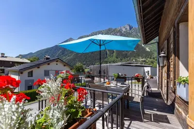 a balcony with a blue umbrella and a table at Heart of Chamonix Lovely and cosy 2 bedrooms, terrace, parking in Chamonix-Mont-Blanc