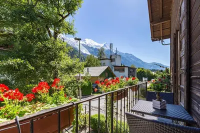 a balcony with a table and flowers and a mountain at Heart of Chamonix Lovely and cosy 2 bedrooms, terrace, parking in Chamonix-Mont-Blanc