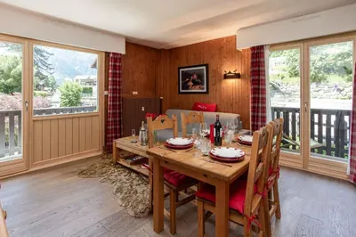 a dining room with a table and chairs and windows at Le Brevent 2 Apartment - Chamonix All Year in Chamonix-Mont-Blanc