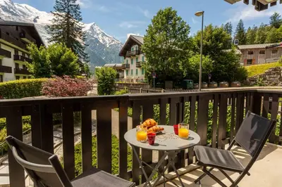 a table with two chairs and drinks on a balcony at Le Brevent 2 Apartment - Chamonix All Year in Chamonix-Mont-Blanc