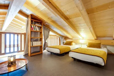 a room with two beds and a book shelf at Chalet Ciscana Chamonix MontBlanc in Chamonix-Mont-Blanc