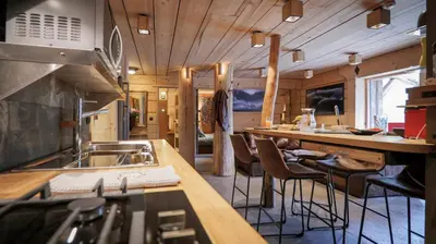 a kitchen with a sink and a counter with chairs at Lodge plein pied avec jardin à 10min de Chamonix in Servoz