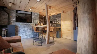 a kitchen with a bar with stools and a tv at Lodge plein pied avec jardin à 10min de Chamonix in Servoz