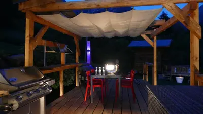 a patio with a table and chairs and a stove at Lodge plein pied avec jardin à 10min de Chamonix in Servoz