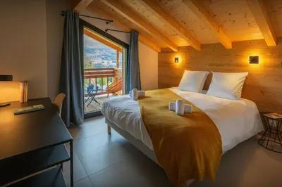 a bedroom with a bed and a large window at MontCriou - OVO Network in Samoëns